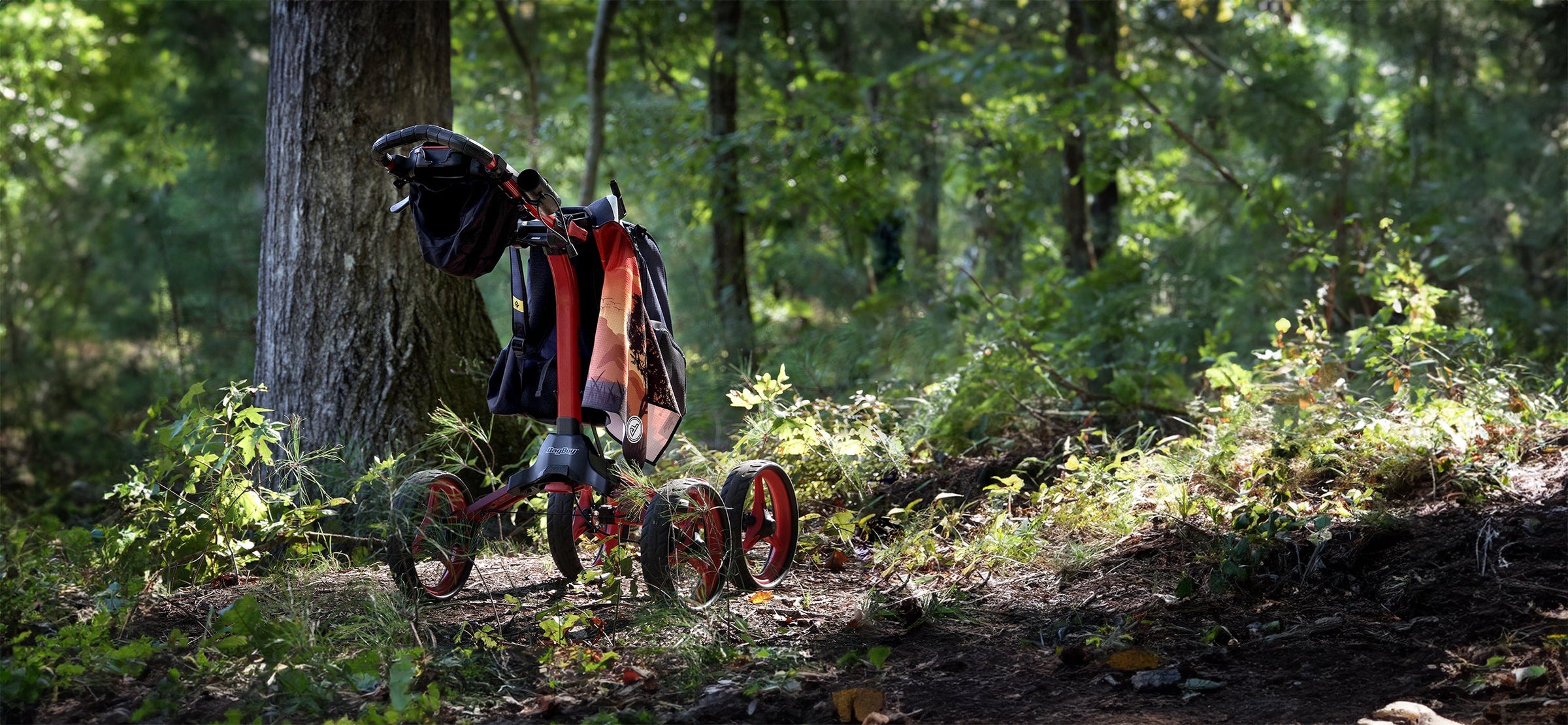 disc golf push cart with towel hanging from it in the woods