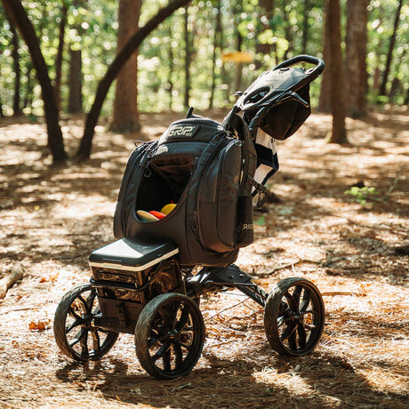 disc golf push cart with towel hanging from it in the woods