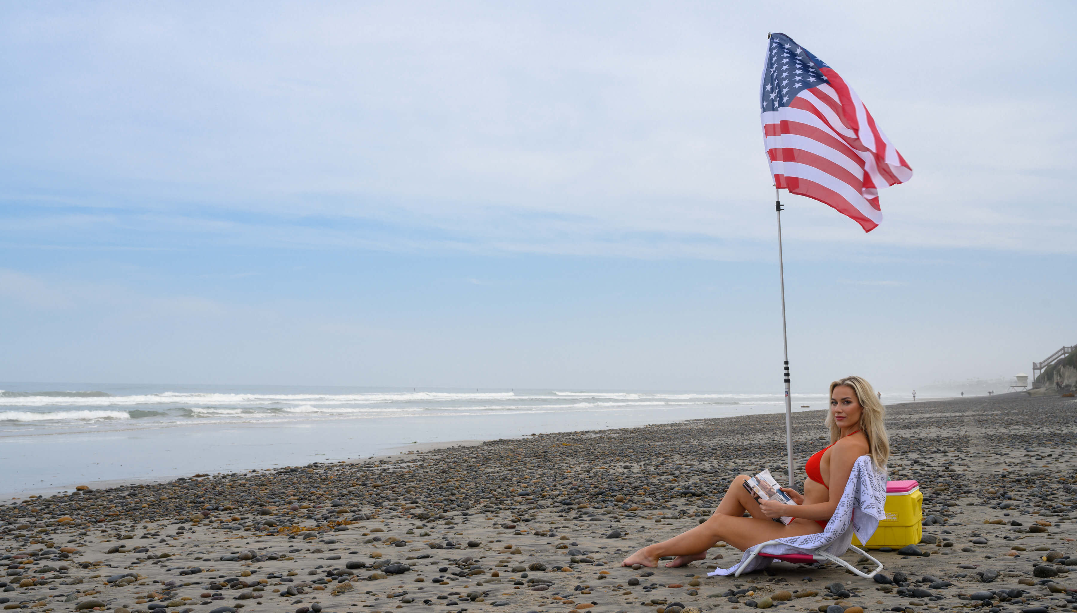 Woman sitting on beach with extendable flag pole setup 