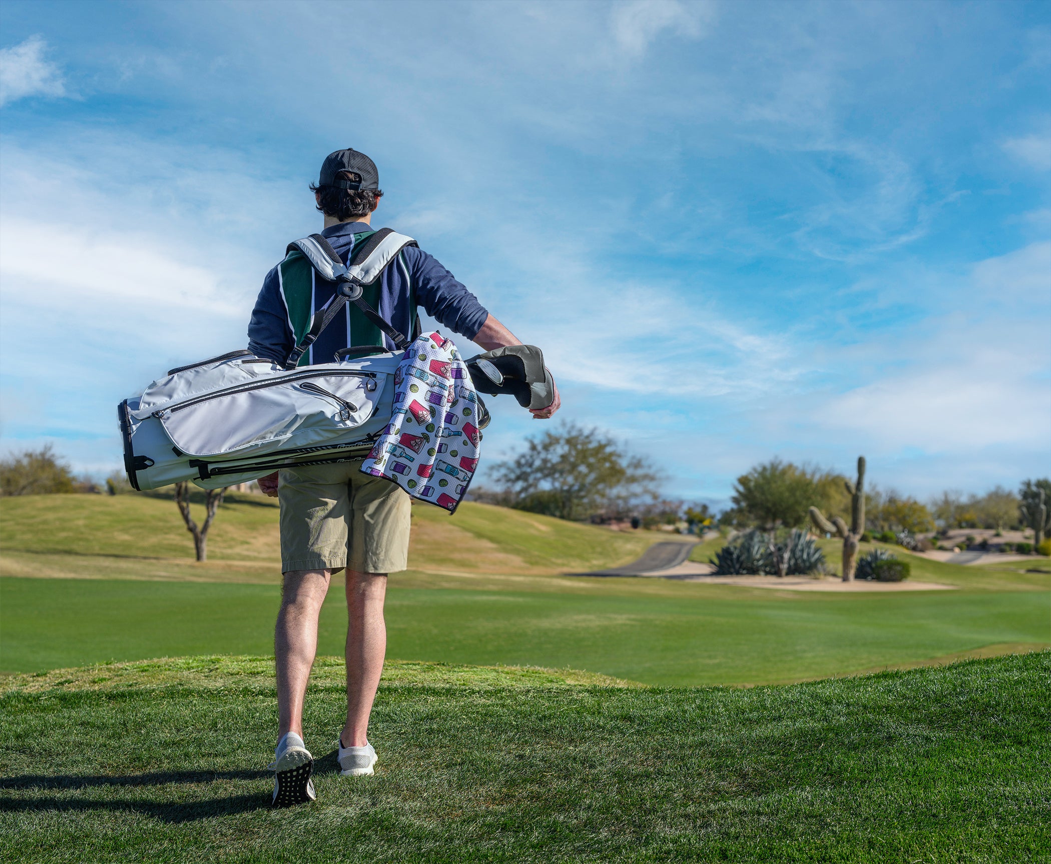 Man standing on golf course with a golf bag on his back and a towel hanging from it