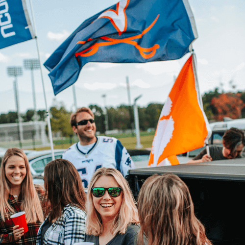 two collegiate flags flying at tailgate